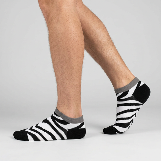 Side view of zebra print ankle socks worn mid-step, black and white low cut novelty socks