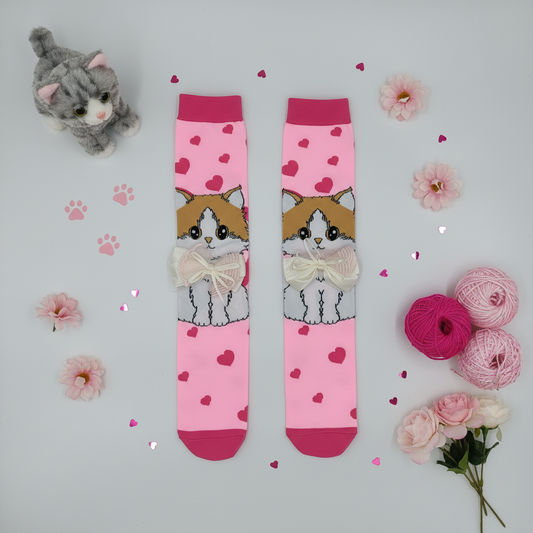 Studio flat lay of pink cat socks with themed props on white background