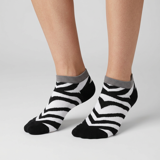 Black and white striped zebra ankle socks with chevron detail, worn on foot, front three-quarter view